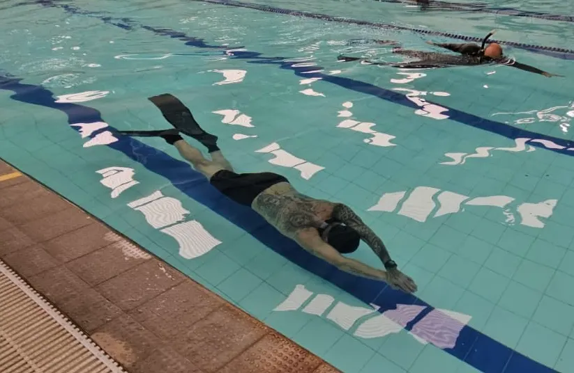 Apneísta nadando con aletas separadas en pileta