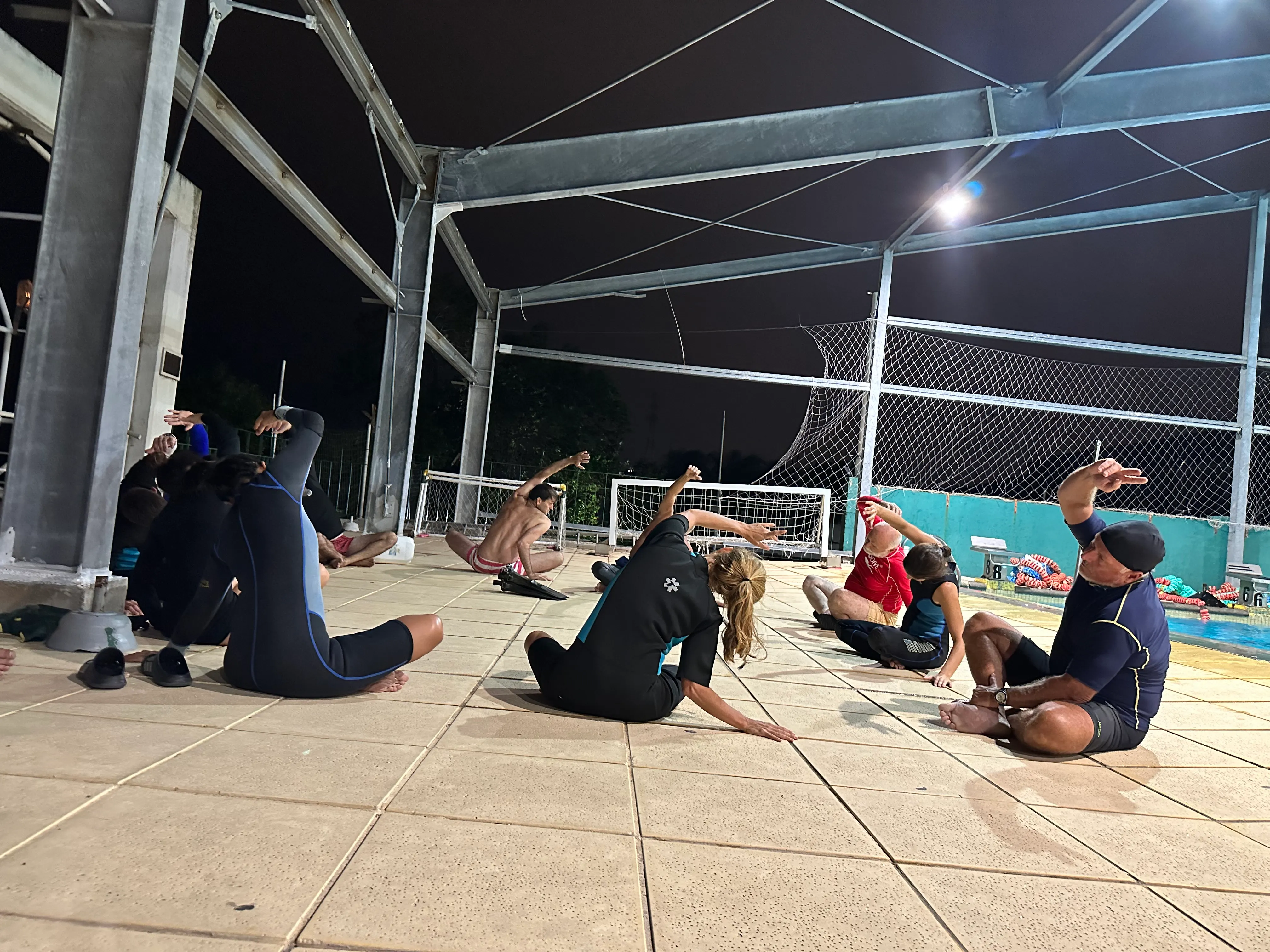 Grupo haciendo estiramiento nocturno junto a la pileta